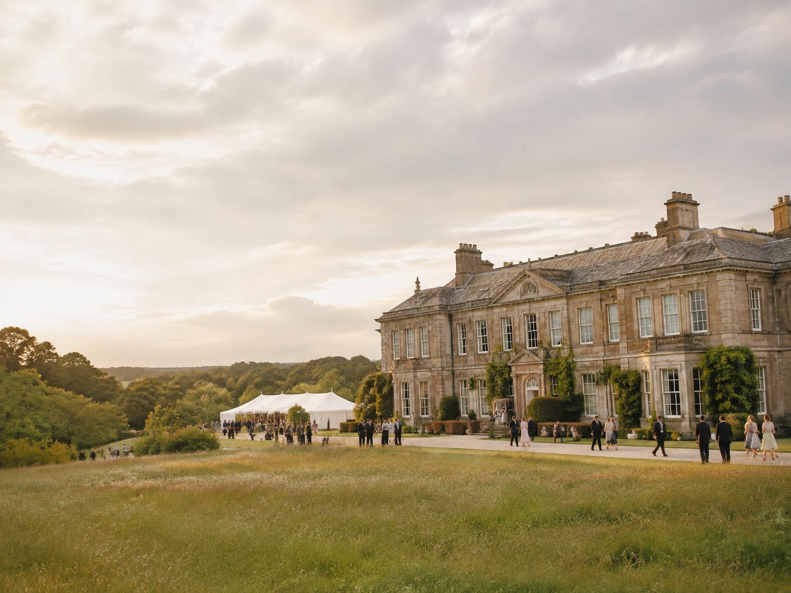 Guests on the lawn of an English Georgian manor with a marquee