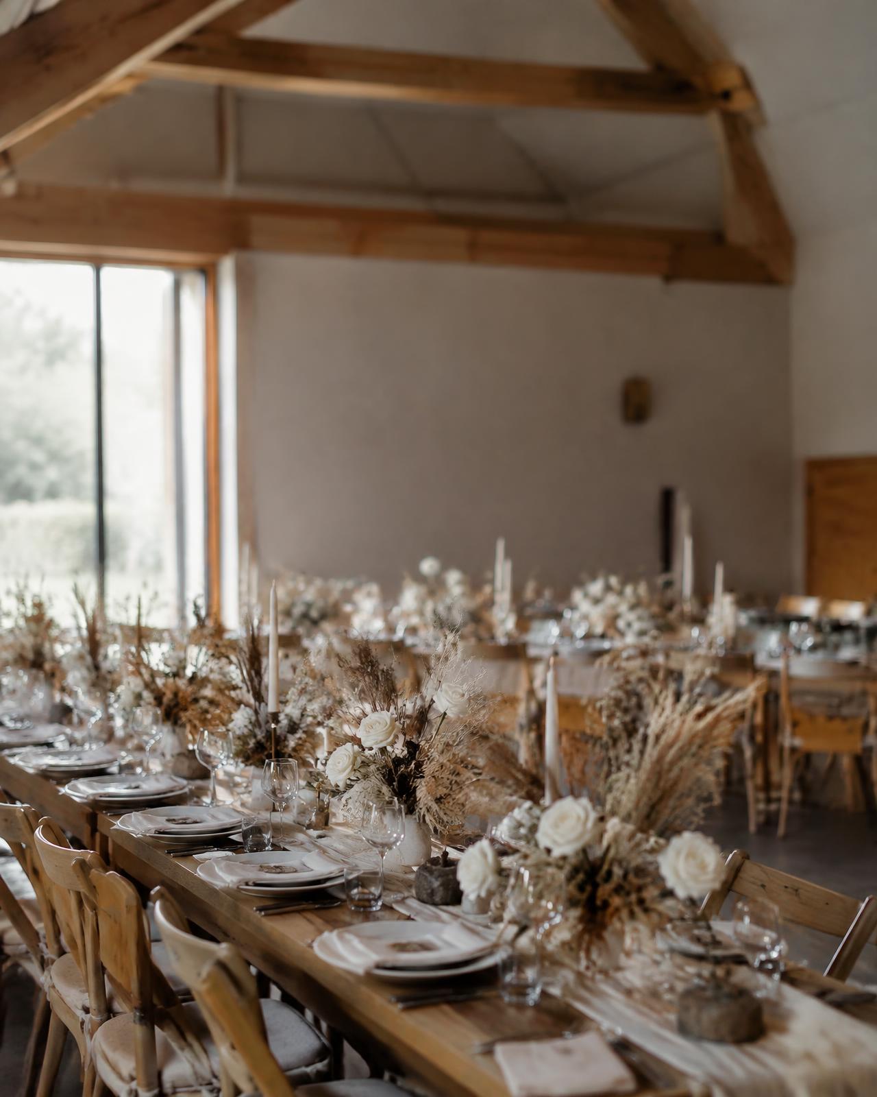 Long timber tables with dried grasses in a contemporary barn venue